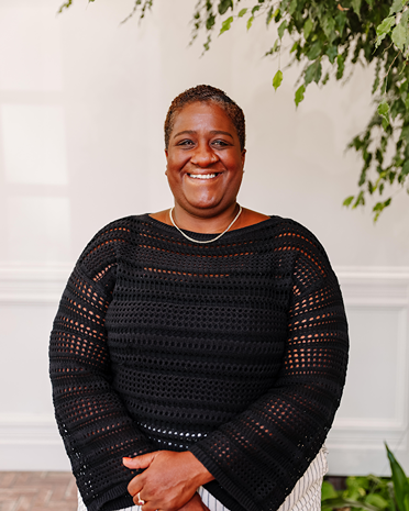 Stacia Ponce-Rodriguez portrait. Smiling woman with short hair in black sweater. Professional headshot with natural lighting.