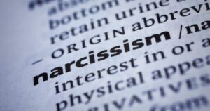 Close-up of a dictionary page highlighting the word narcissism in bold letters.