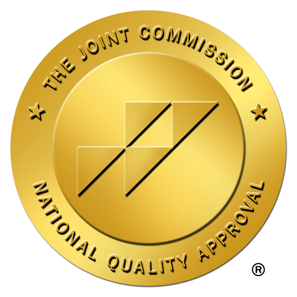 Gold seal badge reading 'The Joint Commission National Quality Approval' with a geometric central logo on a black background (award seal).